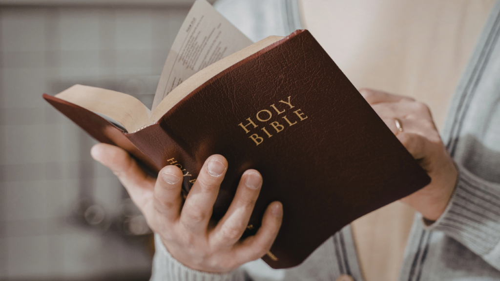 Christian woman holding an open Holy Bible, reflecting the intentional Scripture presence of a Christ-centered home